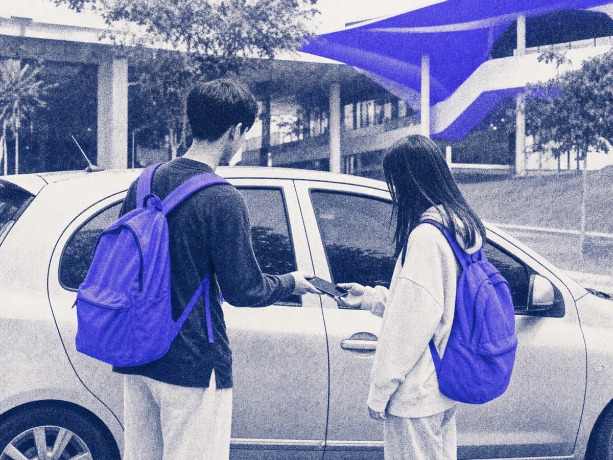 Two students by a car checking details on a phone